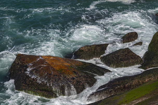  Meereswellen brechen auf einem Felsen in Brasilien. Tiefblaue Meereswellen treffen auf Klippen. Meereswellen prallten auf Felswände. Mächtige Wellen brechen an einer Klippe auf. Wellen, die über Felsen schwappen. Starke Meereswellen treffen auf Felsen  - Foto, Bild