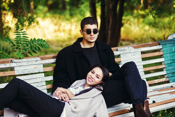 Nuori rakastava pari istuu penkillä kaupungin puistossa
 . - Valokuva, kuva