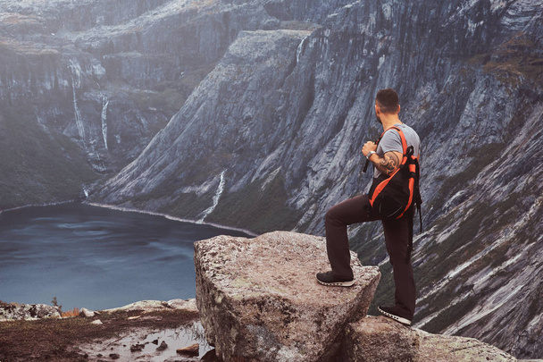 Turystycznych stoi na szczycie góry z niesamowitym widokiem na norweski fiord. - Zdjęcie, obraz