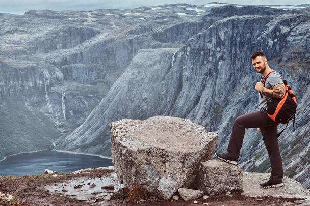 Turista fica no pico da montanha com uma vista incrível do fiorde norueguês
. - Foto, Imagem