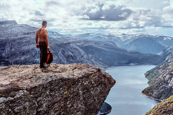 Touristenmann steht in der Trolltunga und genießt einen schönen Blick auf den norwegischen Fjord. - Foto, Bild