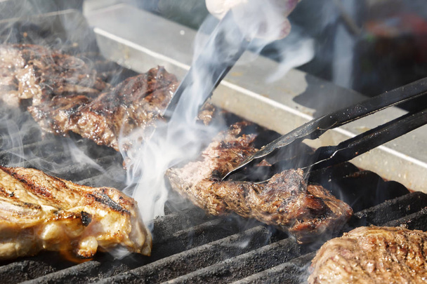 Руки повара с ножом проверить готовность мяса стейк готовится на горячем гриле
 - Фото, изображение