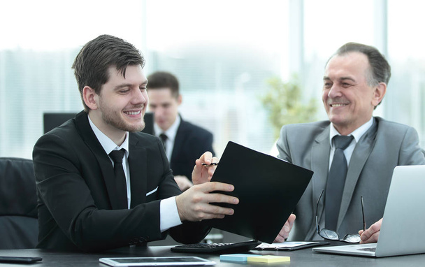adult businessman discussing financial documents with a young colleague. - Photo, Image