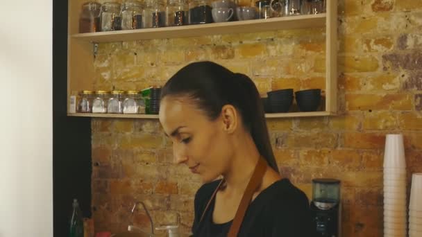 An attractive girl (the owner of a coffee house) works on a tablet. - Footage, Video