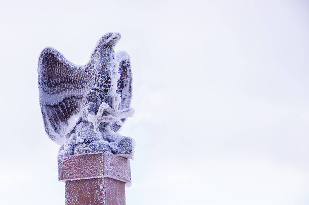 La estación de esquí está cubierta de nieve con una estatua de águila en la cima de la montaña y el cielo cubierto de nieve en el fondo
 - Foto, Imagen