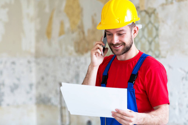 Building engineer arranging technical details via mobile phone insuring everything goes smooth in business  - 写真・画像