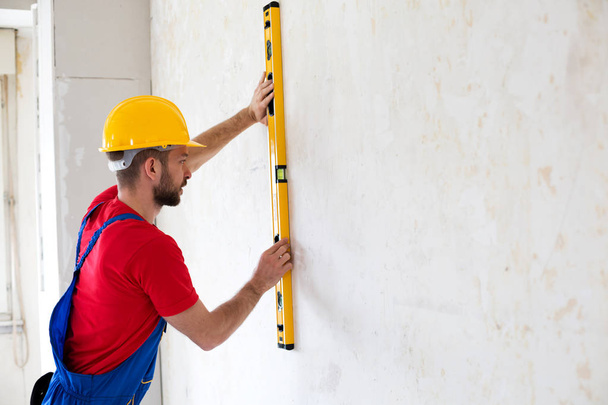 Handyman holding water level and checking the adjustment to a wall surface  - Foto, imagen