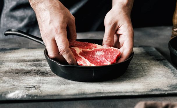 Man cooking beef steak on dark background  - Фото, зображення