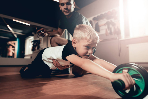 Sporty Child Is Doing Exercises With The Gym Wheel. Parenthood Relationship. Sporty Family Concept. Active Lifestyle. Press Exercise. Holiday Leisure. Working Out Together. Fitness Day. - Photo, image
