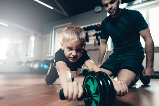Sporty Child Is Doing Exercises With The Gym Wheel. Parenthood Relationship. Sporty Family Concept. Active Lifestyle. Press Exercise. Holiday Leisure. Working Out Together. Fitness Day. - Foto, immagini