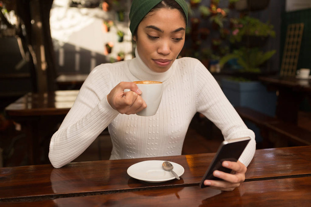 Belle femme utilisant un téléphone mobile tout en prenant un café dans le café
 - Photo, image