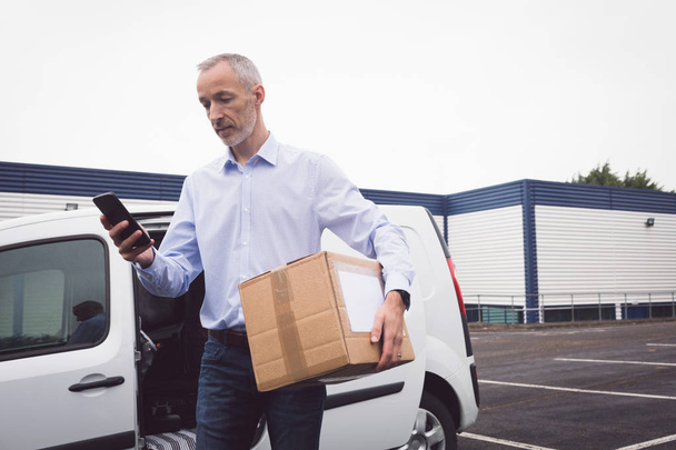 Delivery man using mobile at warehouse  - Photo, Image