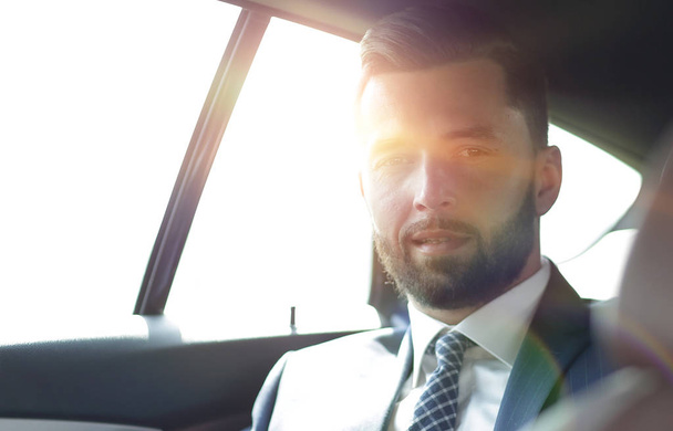 handsome bearded businessman sitting on back seat of car - Foto, imagen