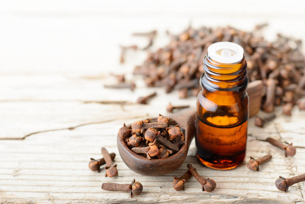 clove essential oil in the glass bottle, on the wooden table - 写真・画像