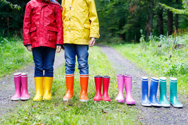 Küçük çocuklar, oğlanlar ve kızlar renkli yağmur botları. Sonbahar ormanda duran çocuk. Close-up schoolkids ve farklı lastik çizme. Ayakkabı ve moda yağmurlu sonbahar için - Fotoğraf, Görsel