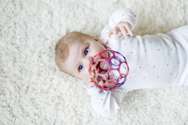 Cute baby girl gry z kolorowe grzechotka zabawki - Zdjęcie, obraz