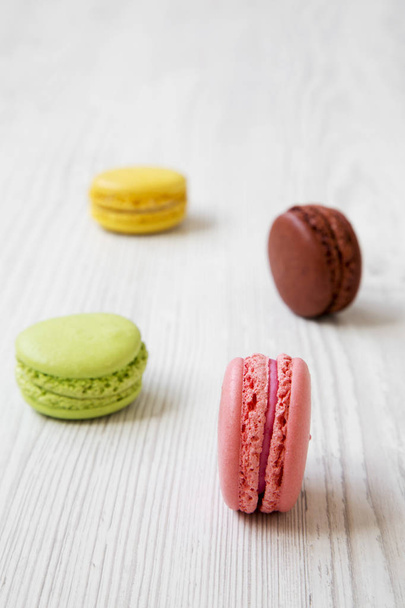 Sweet and colorful macaroons on a white wooden background, side view. Selective focus. - Fotografie, Obrázek