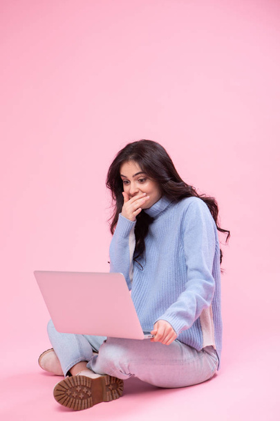 Student holding laptop. Love to computer concept. Attractive female half-length front portrait, trendy pink studio backgroud. Young emotional pretty woman. Human emotions, facial expression - Photo, Image