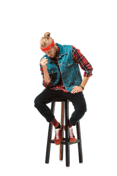 hipster man in denim vest and red checkered shirt sitting on chair isolated on white  - Foto, immagini