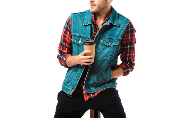 vista parziale del gilet in denim hipster seduto sulla sedia con tazza di caffè isolato su bianco
 - Foto, immagini