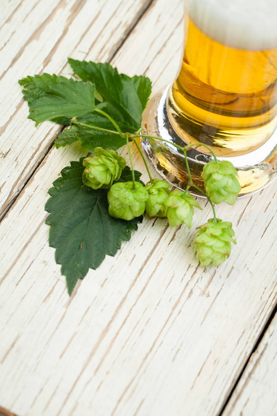 Beer glass and hops plant on wooden background with copy space, top view - Photo, Image