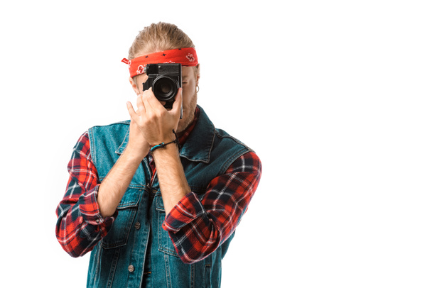 concentrated hipster male photographer in denim vest and checkered shirt shooting on camera isolated on white - Photo, Image