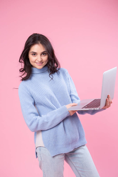 Estudiante sosteniendo laptop. Me encanta el concepto de computadora. Atractivo retrato delantero femenino de media longitud, fondo de estudio rosa de moda. Joven mujer bonita emocional. Emociones humanas, expresión facial
 - Foto, imagen