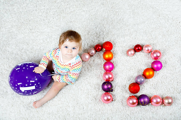 Schattig babymeisje houdt van kleurrijke vintage xmas speelgoed bal in schattig handen. Kleine kind en kerstboom ballen als twaalf. - Foto, afbeelding