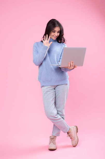 Студент держит ноутбук. Любовь к компьютерной концепции. Привлекательный женский полудлинный фронтальный портрет, модная розовая студия. Молодая эмоциональная красотка. Человеческие эмоции, выражение лица
 - Фото, изображение