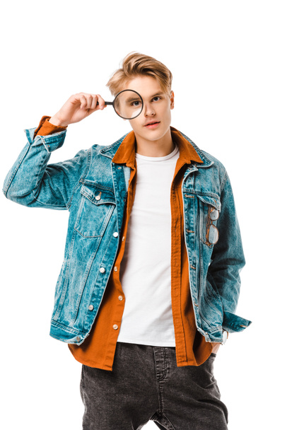 handsome young hipster man in denim jacket looking onto magnifier isolated on white - Photo, Image