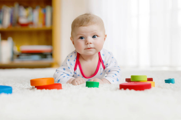 Χαριτωμένο μωρό κορίτσι παίζει με το παιχνίδι πολύχρωμο Ξύλινη κουδουνίστρα - Φωτογραφία, εικόνα