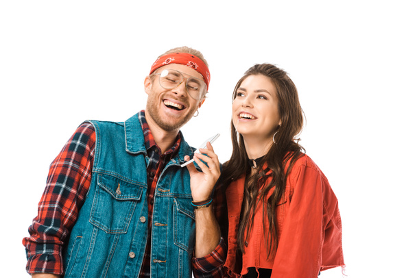 laughing young hipster talking on smartphone while his girlfriend standing near isolated on white - Foto, afbeelding