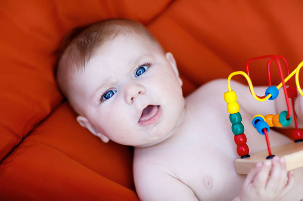 entzückendes neugeborenes Baby spielt mit buntem hölzernem Rasselspielzeug - Foto, Bild