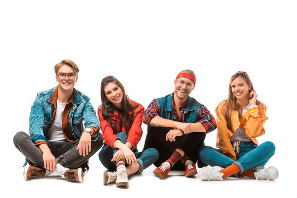 smiling hipster friends sitting on floor and looking at camera isolated on white - Fotoğraf, Görsel