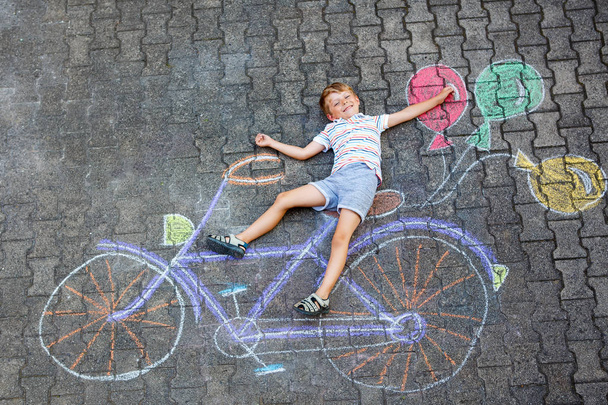 mały chłopiec dziecko zabawy z rowerów chalks obraz na ziemi - Zdjęcie, obraz