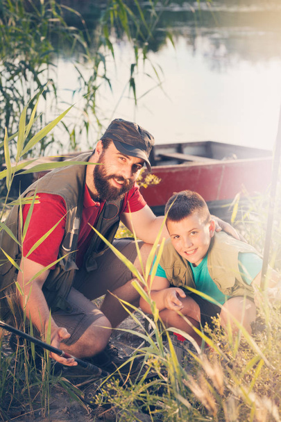 Pai feliz e filho juntos na pesca, preparar o equipamento de pesca que será levado para o barco
 - Foto, Imagem