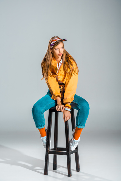 beautiful stylish girl posing on stool on grey - 写真・画像