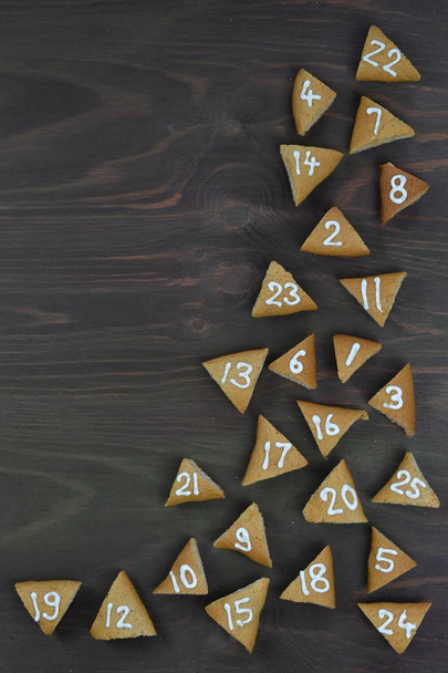 границы двадцати пяти пронумерованных Advent cookies на коричневом дереве с копировальным пространством
 - Фото, изображение