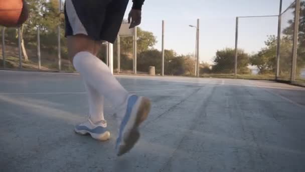 Rare view of a young girl basketball player training and exercising outdoors on the local court. Running with the ball, bouncing and make a shot. Low angle footage - Felvétel, videó