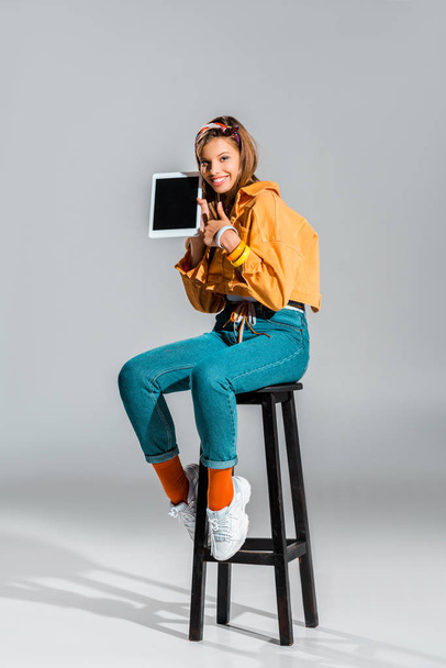 menina bonita mostrando polegar para cima e tablet com tela em branco no cinza
 - Foto, Imagem