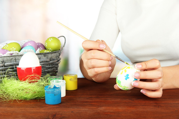 Young woman painting Easter eggs, on bright background - Fotó, kép