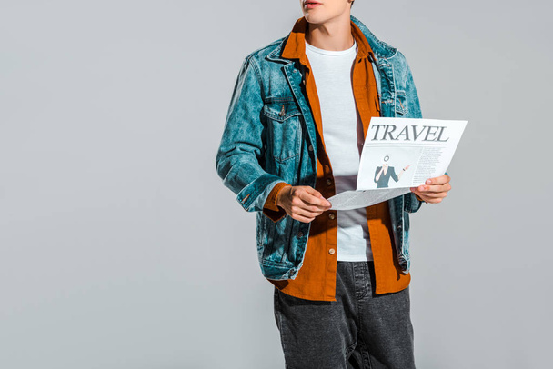 cropped view of hipster in denim jacket reading travel newspaper isolated on grey - Fotografie, Obrázek