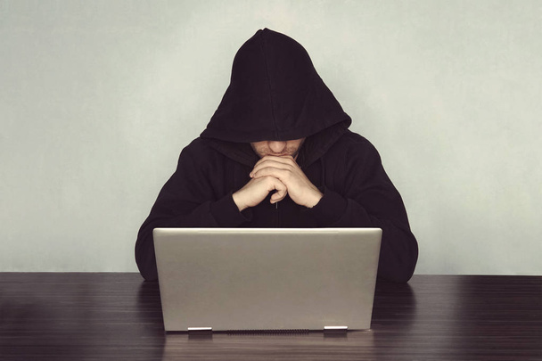 Hacker mit seinem Computerdenken auf hellblauem Hintergrund. Mönchseinsiedler betet vor dem Computer. Konzept der Cyber-Kriminalität und das Hacken elektronischer Geräte - Foto, Bild