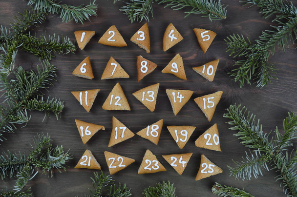 vijf en twintig genummerde komst cookies op bruin hout met pine takken - Foto, afbeelding