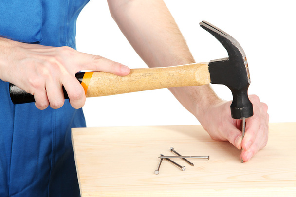 Builder hammering nails into board isolated on white - Φωτογραφία, εικόνα