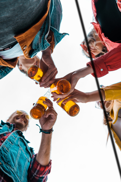 bottom view of happy friends clinking with beer bottles together - Foto, Imagem