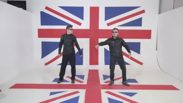 Taniec dwóch atrakcyjnych facetów w czarne skórzane kurtki motocyklowe i okulary przeciwsłoneczne. - Materiał filmowy, wideo
