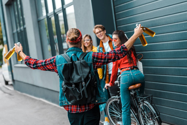 excité hipster mâle a apporté de la bière à des amis heureux dans la rue avec vélo
 - Photo, image