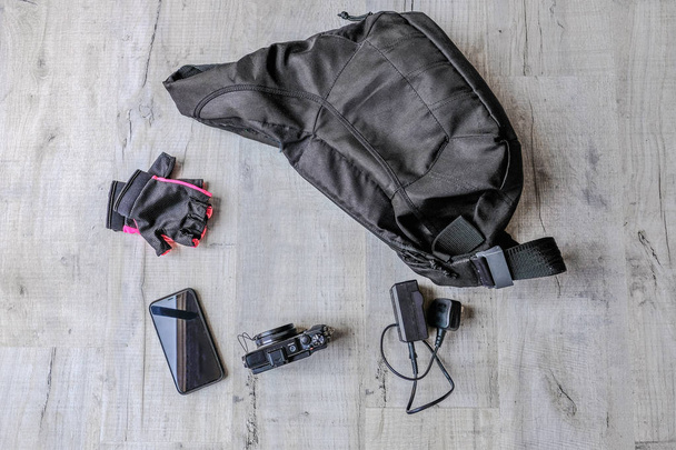 Bolsa de cámara negra con cámara y teléfono inteligente colocada sobre una mesa gris claro. Una expedición planeada
. - Foto, imagen