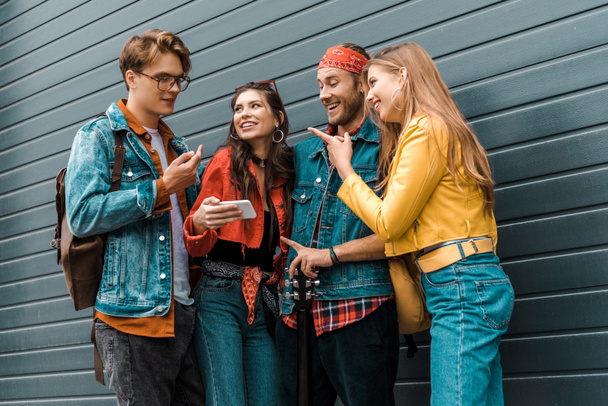 happy young hipsters using smartphone together on street - Photo, Image